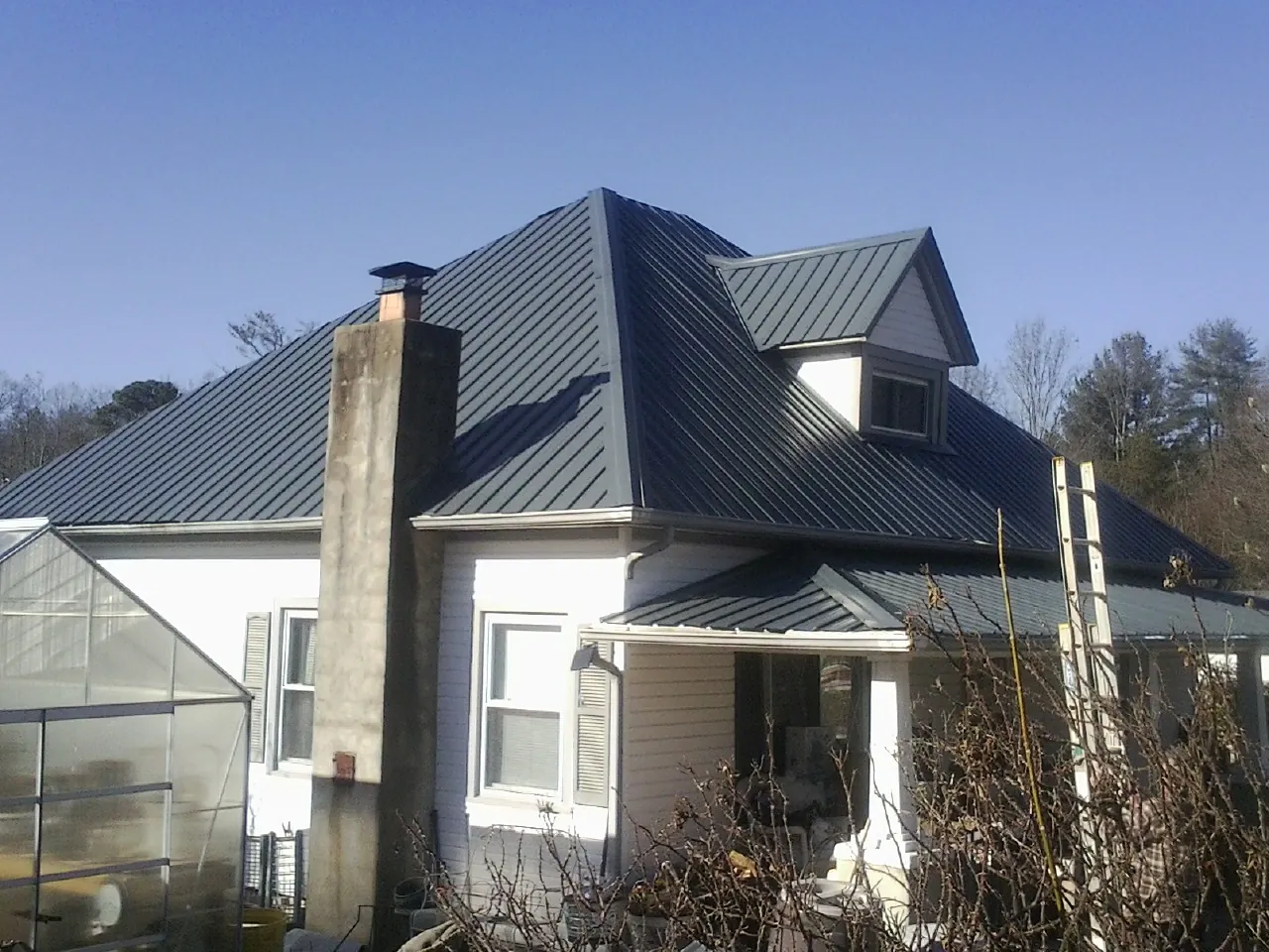 Dark blue standing seam metal roof on a white farmhouse with dormer — Slate & Tile Roof Repair by Roofing Brothers in Ardmore